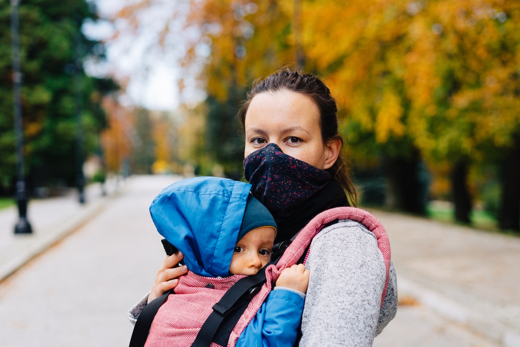Woman wearing mask with baby in carrier