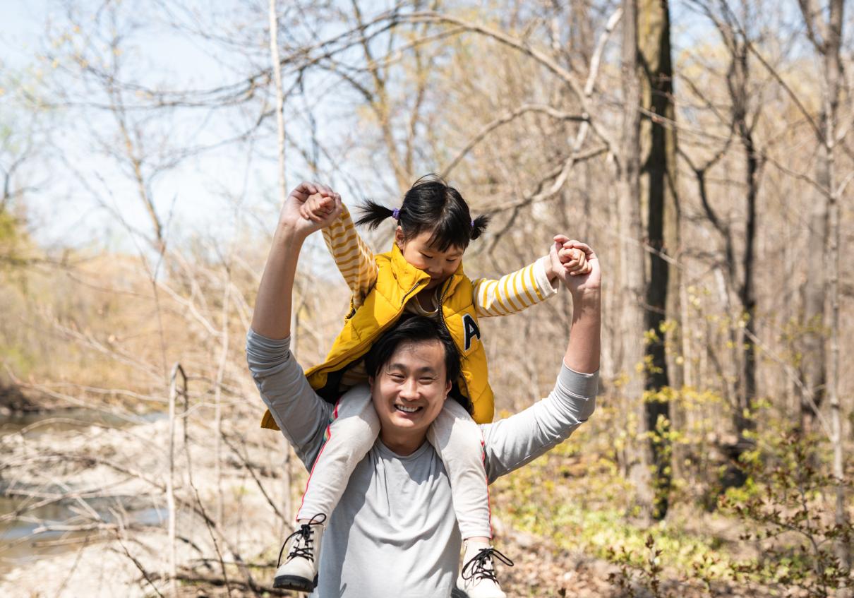 Man joyfully giving his daughter a ride on his shoulders