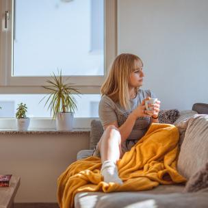 Woman with blanket and coffee on couch