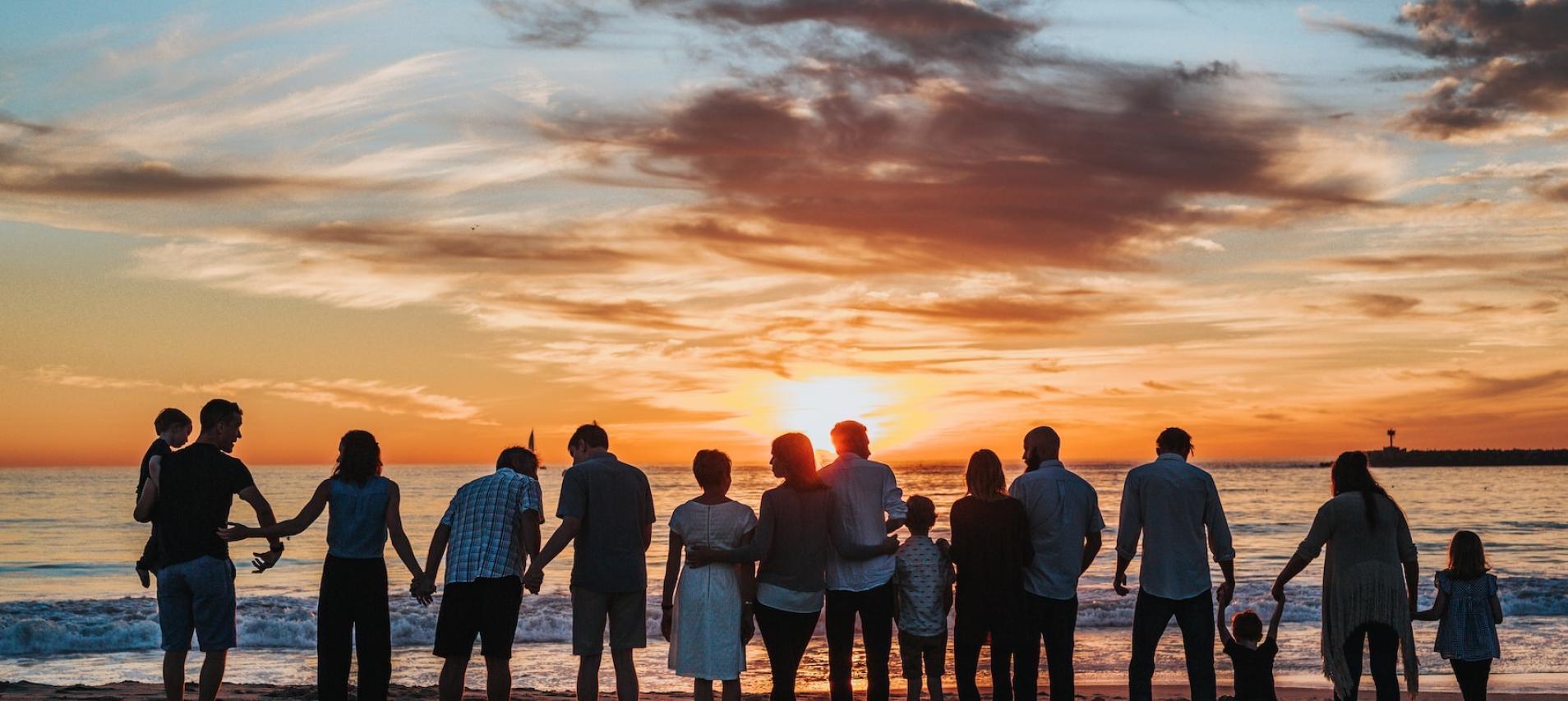 multiple families facing sunset on a beach